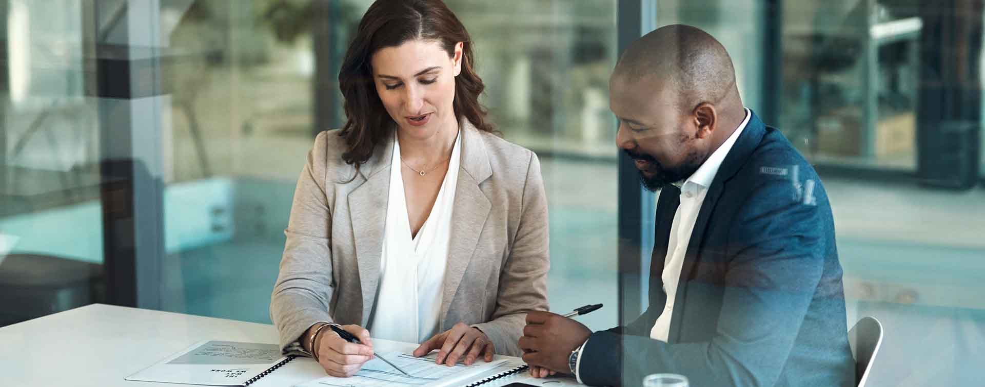 Two businesspeople meeting in an office looking over documents