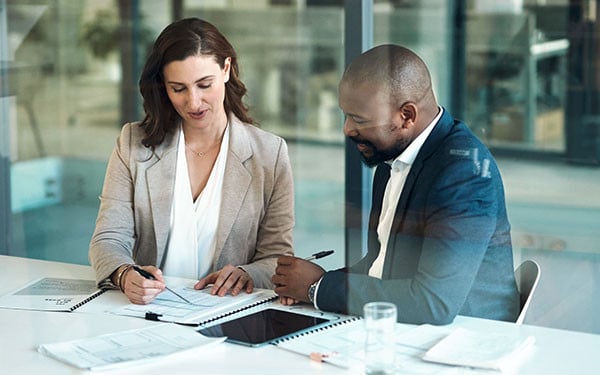 Two businesspeople meeting in an office looking over documents