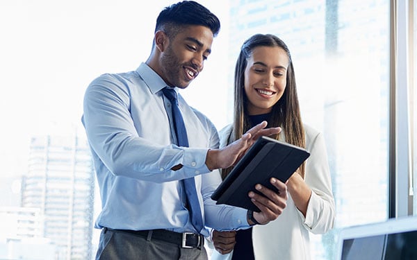 Two smiling businesspeople looking at something on a tablet