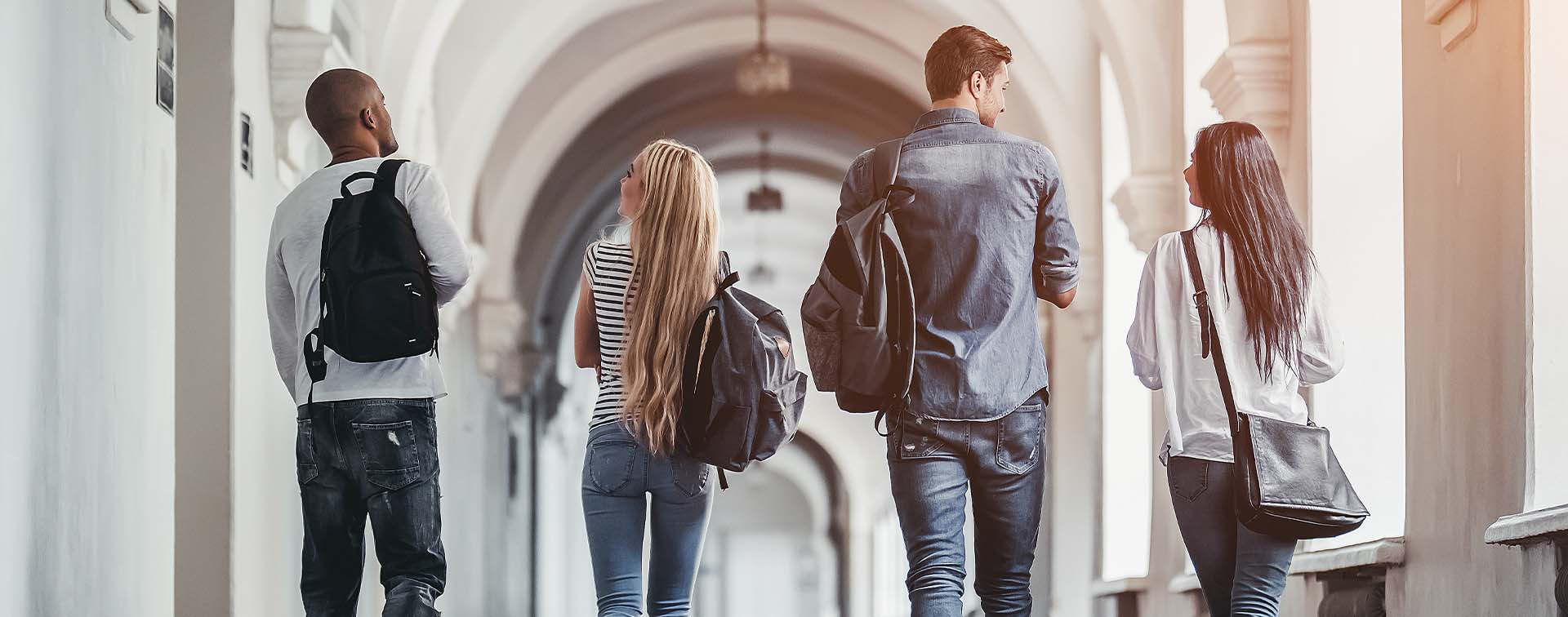 University students carrying backpacks walking in a corridor
