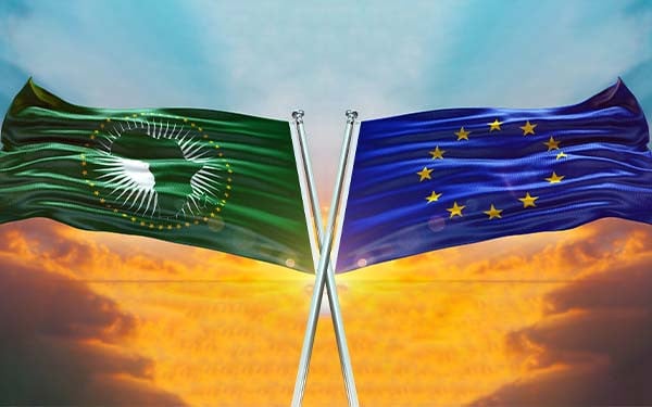 The waving UN flag crossed over the African Union flag in front of a sky at sunset.