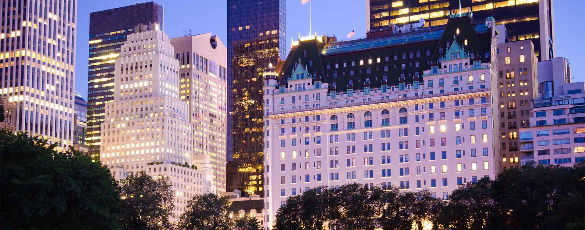 Plaza Hotel and other buildings as seen from Central Park in New York City, USA, lit up in the evening